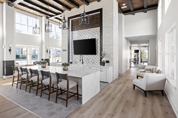 A modern kitchen with a long white island and a television mounted above it.